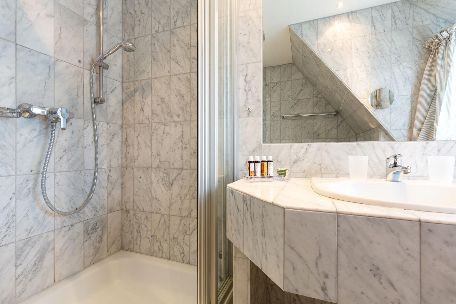 Bathroom with marble wall, shower, and sink