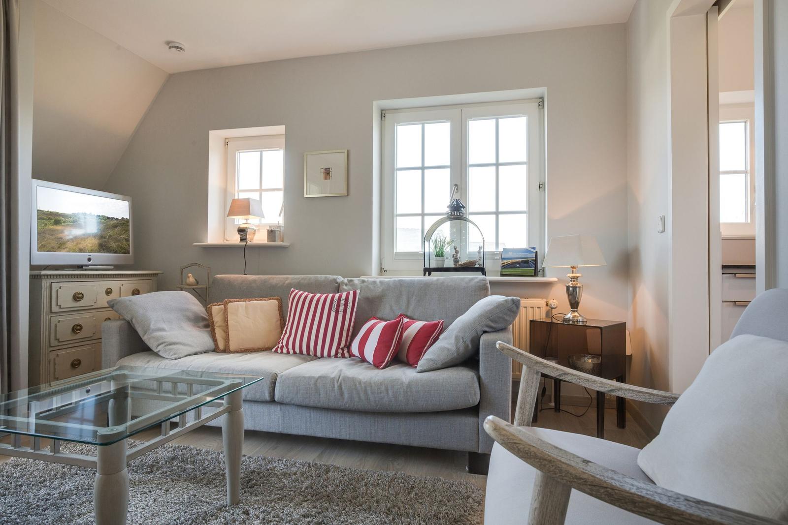 Living room with sofa, glass table, and windows.