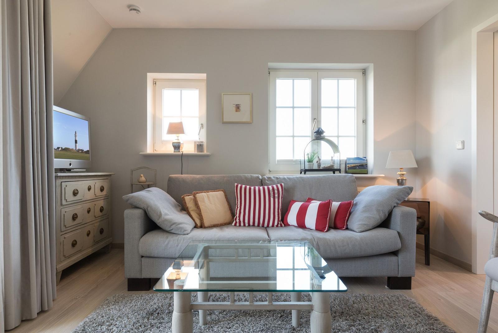 Living room with sofa, glass table, and windows