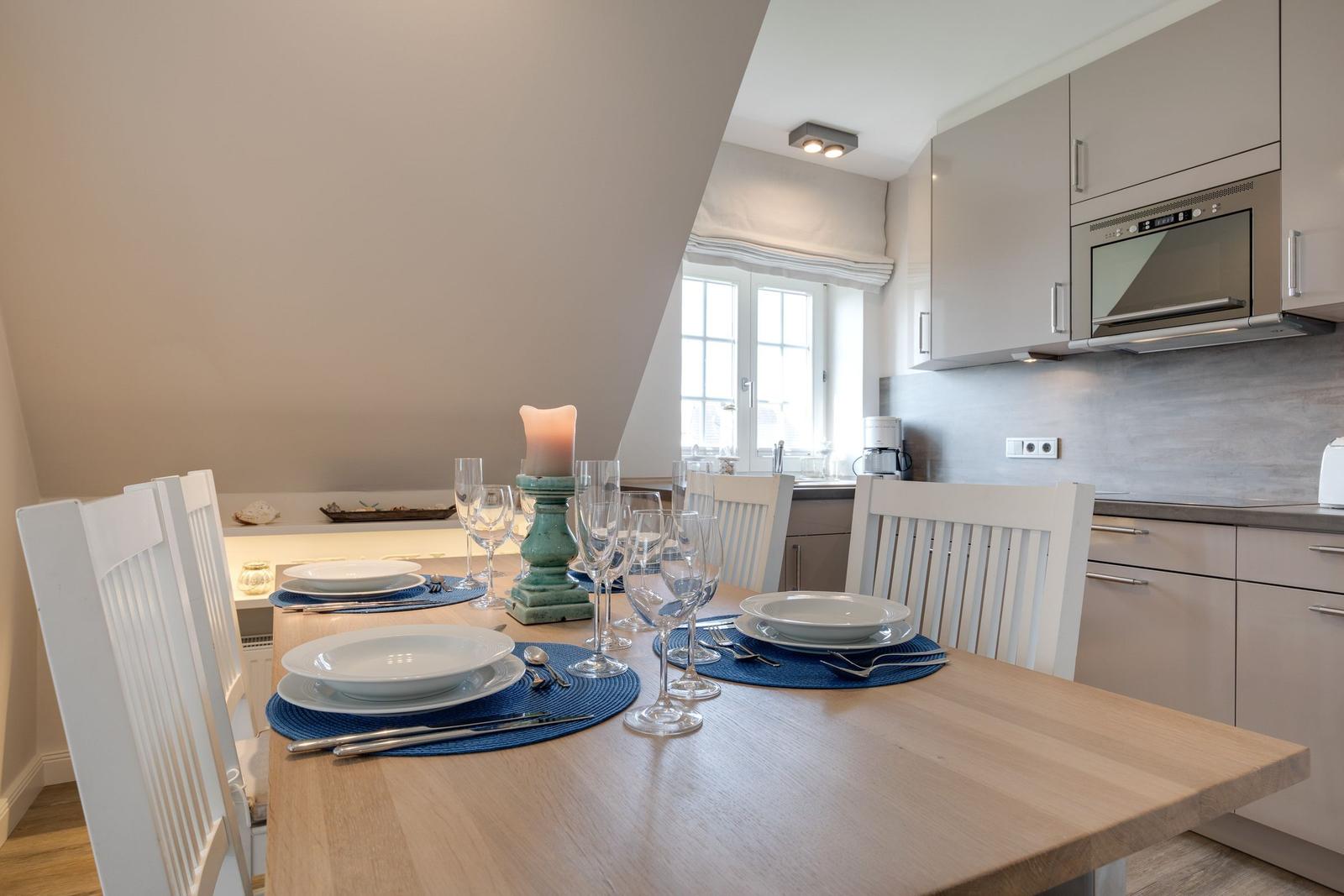 Dining table for four, kitchen area, and window in the background.