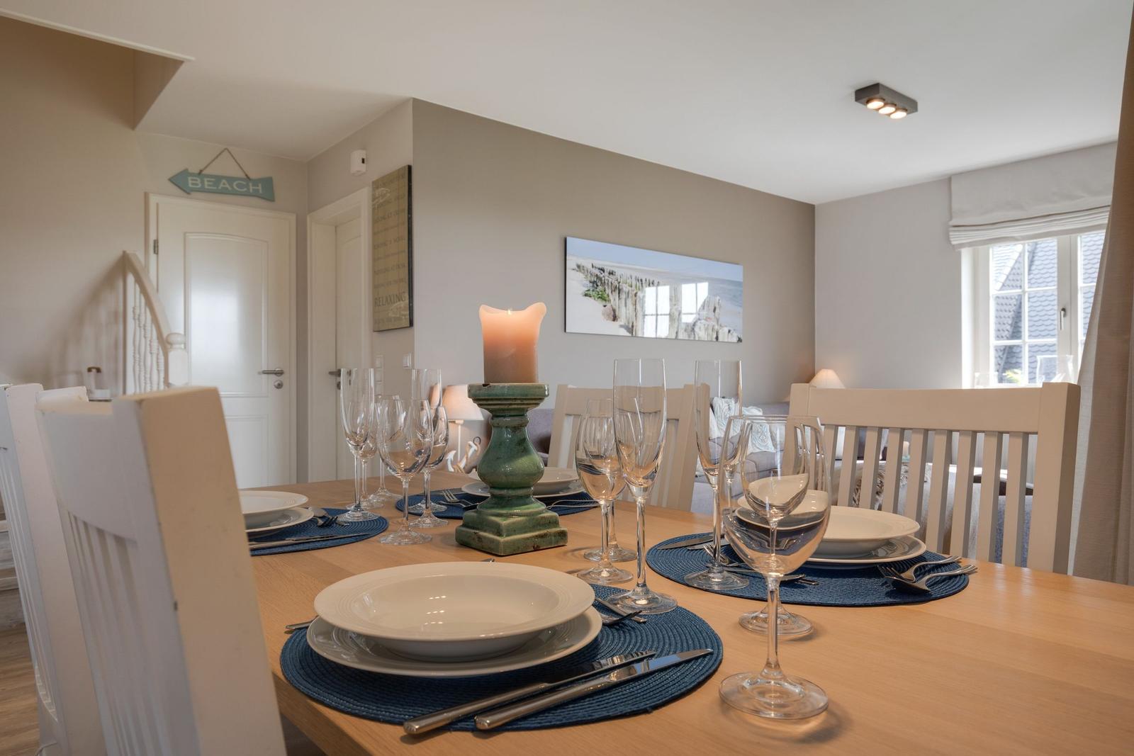 Dining room with set table, white chairs, and wall art