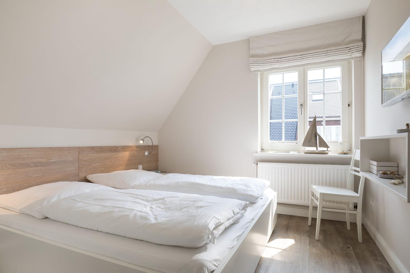 Bedroom with double bed, window, and desk.