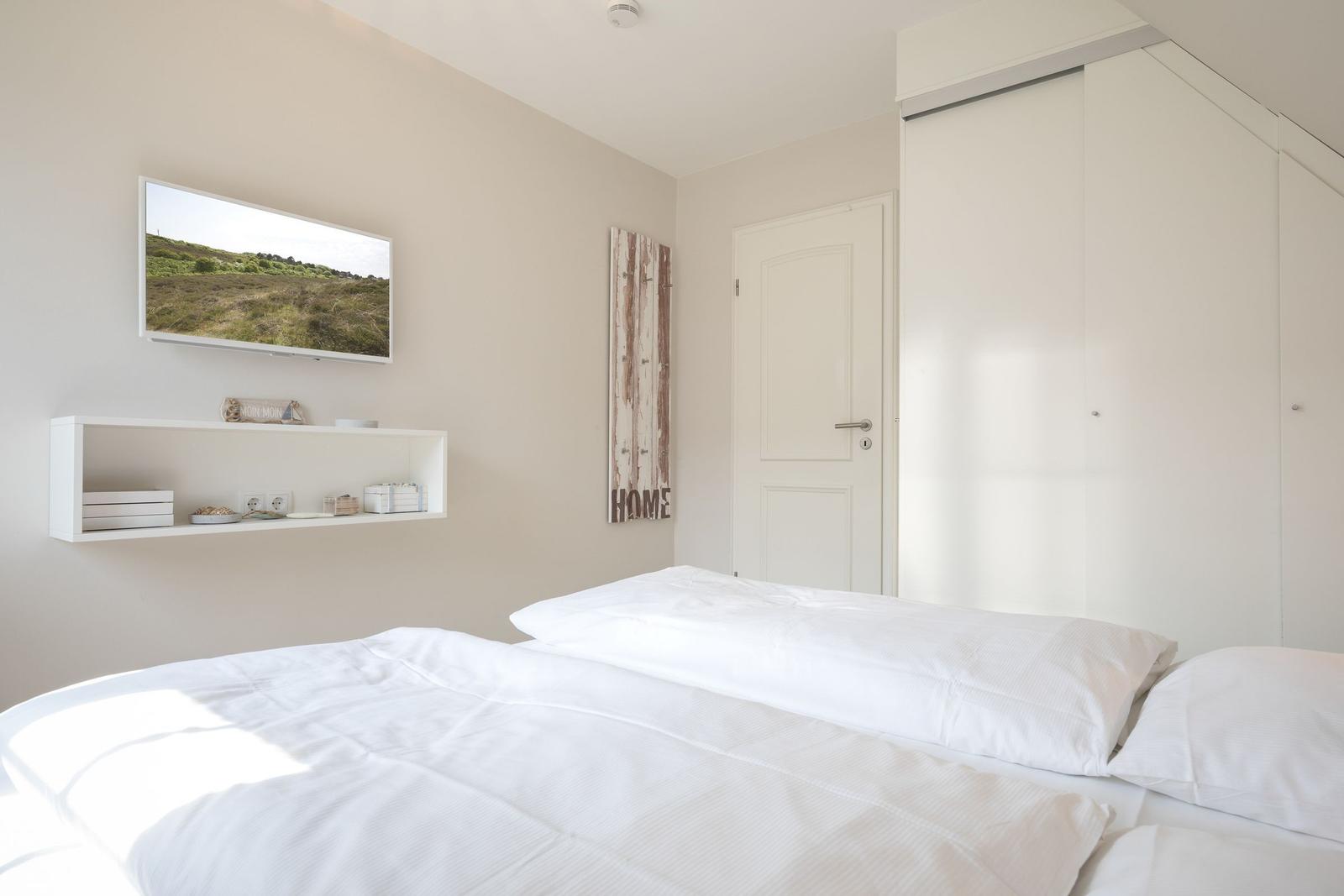 Bedroom with white bed, closet, and wall art.
