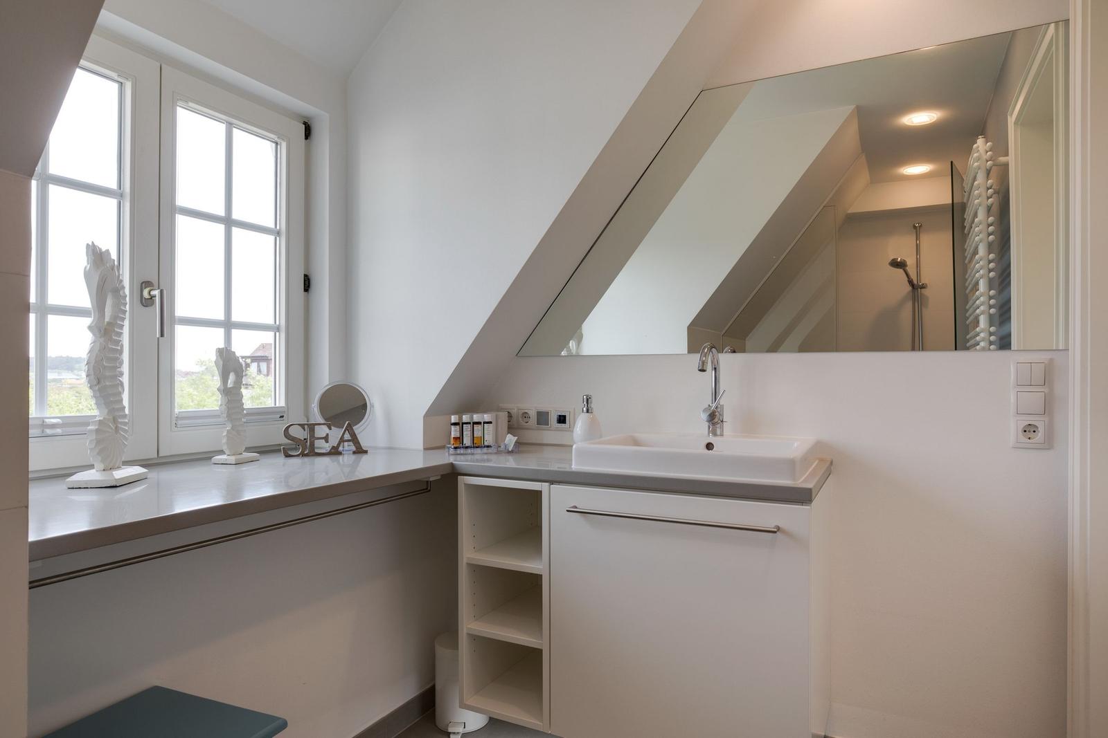 Bathroom with sink, mirror, and window. Attic with sloped ceiling.