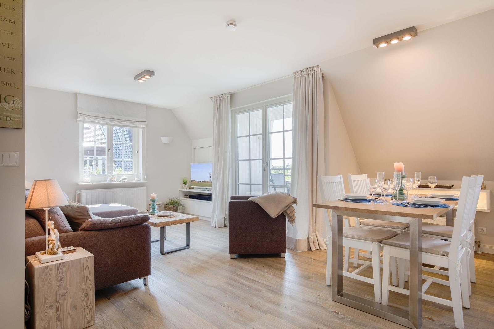 Living and dining area with wooden floor, sofa, dining table, and windows.