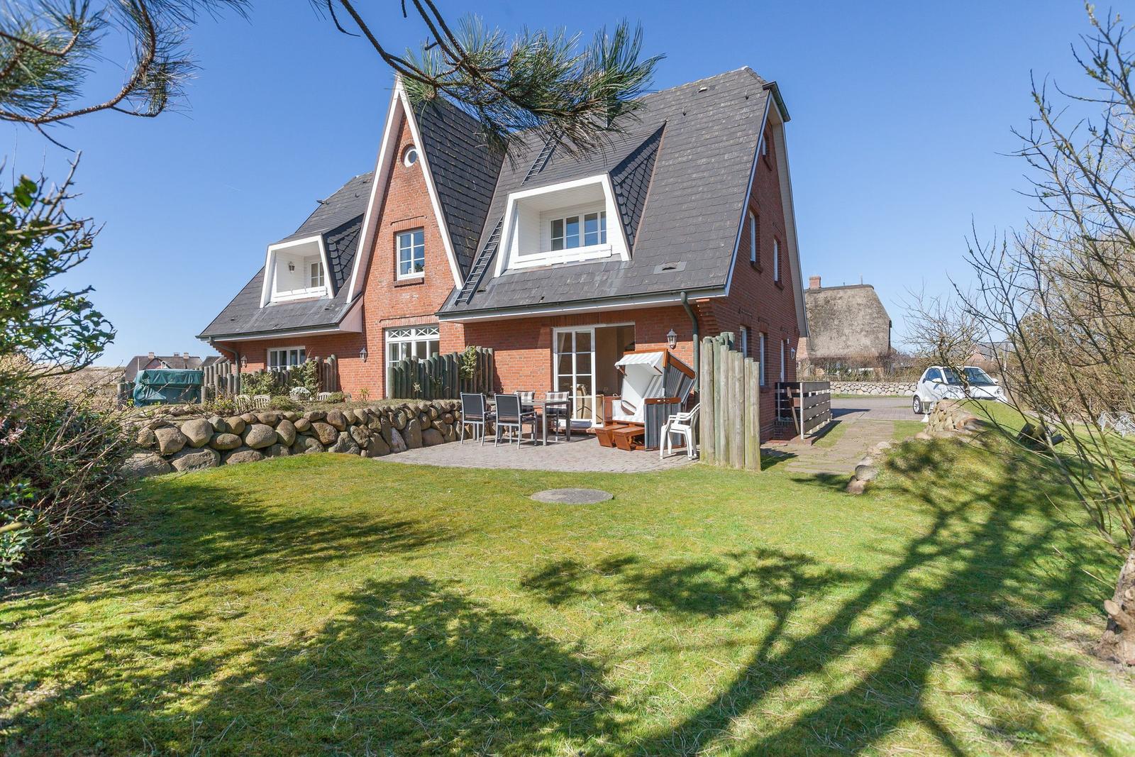 Rotes Backsteinhaus mit Terrasse und Garten. Grillplatz und Strandkorb vorhanden.