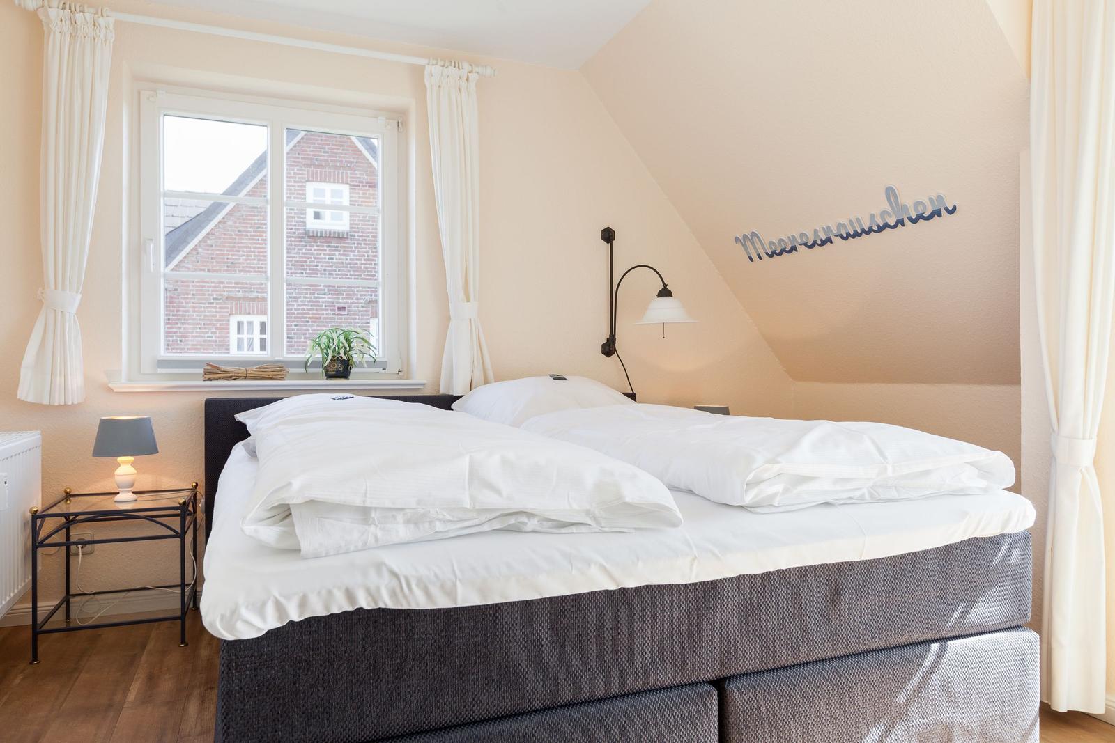Schlafzimmer mit Doppelbett, Fenster und Wanddekoration.