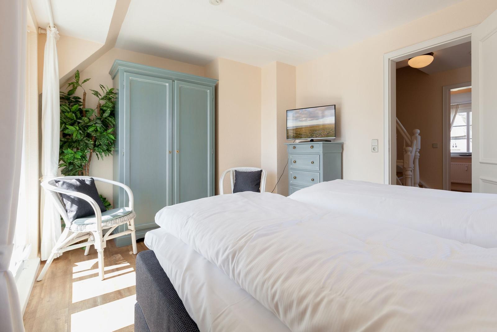 Schlafzimmer mit Doppelbett, Kleiderschrank und Fernseher.