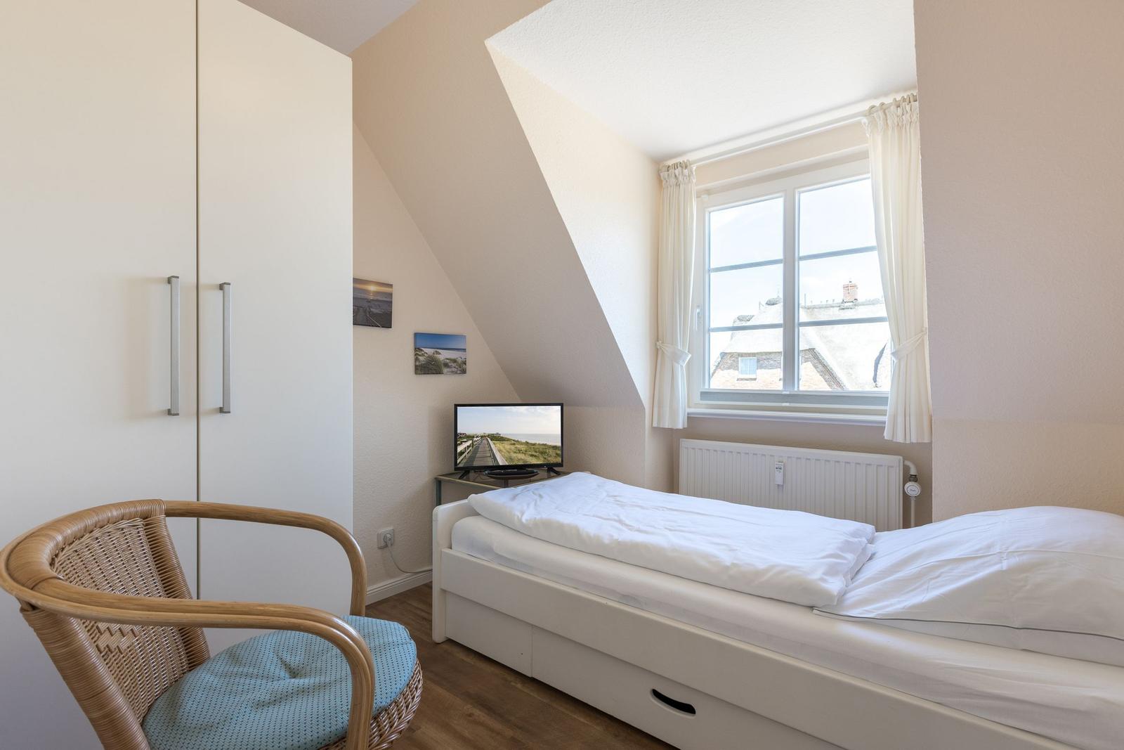 Schlafzimmer mit Dachschräge, Bett, TV und Stuhl