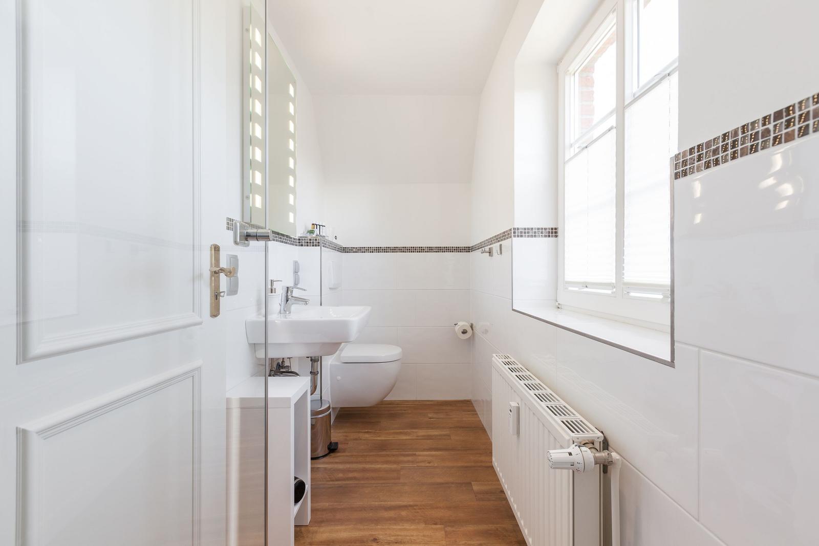 Badezimmer mit Waschbecken, Toilette und Fenster