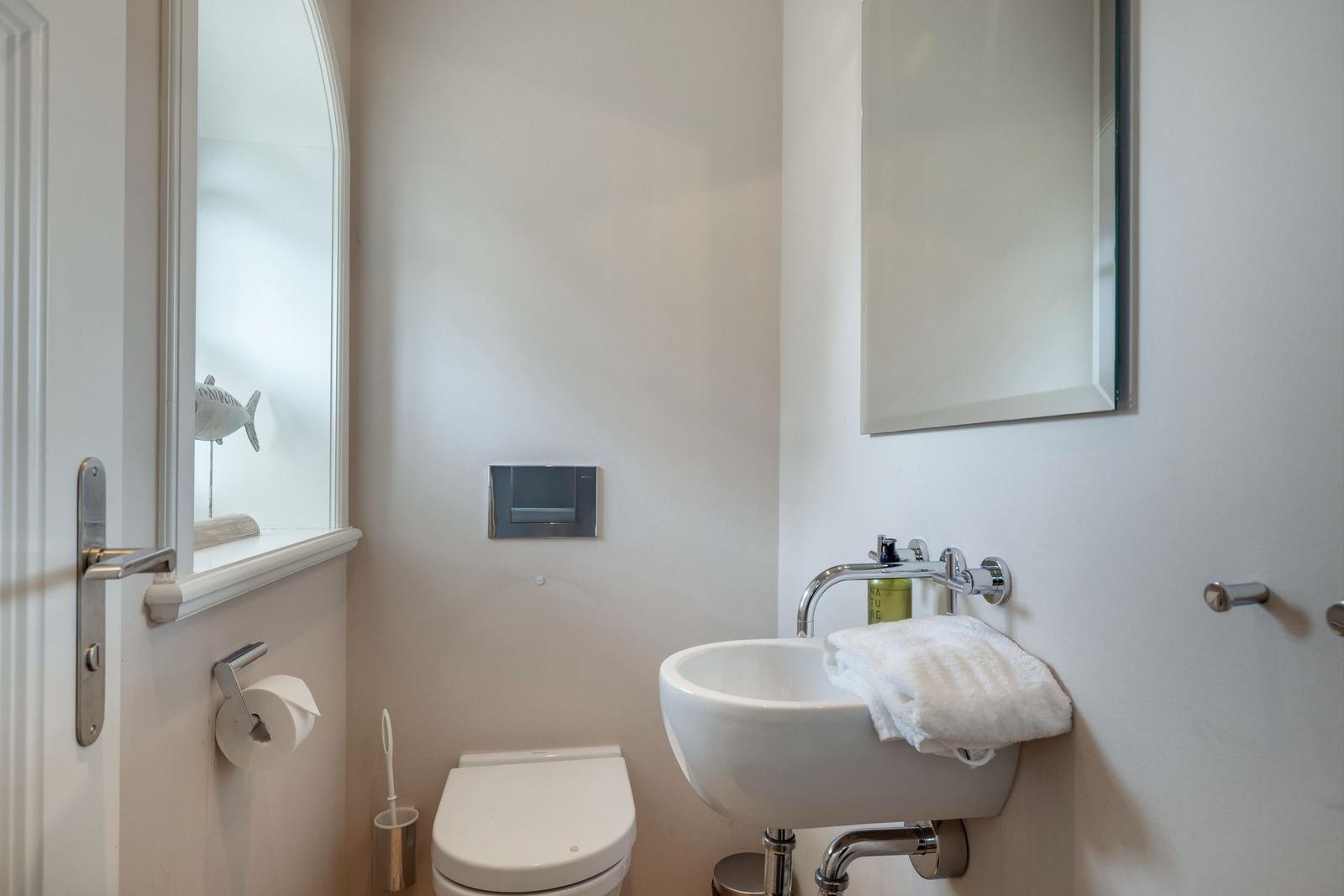 Badezimmer mit Toilette, Waschbecken und Spiegel.