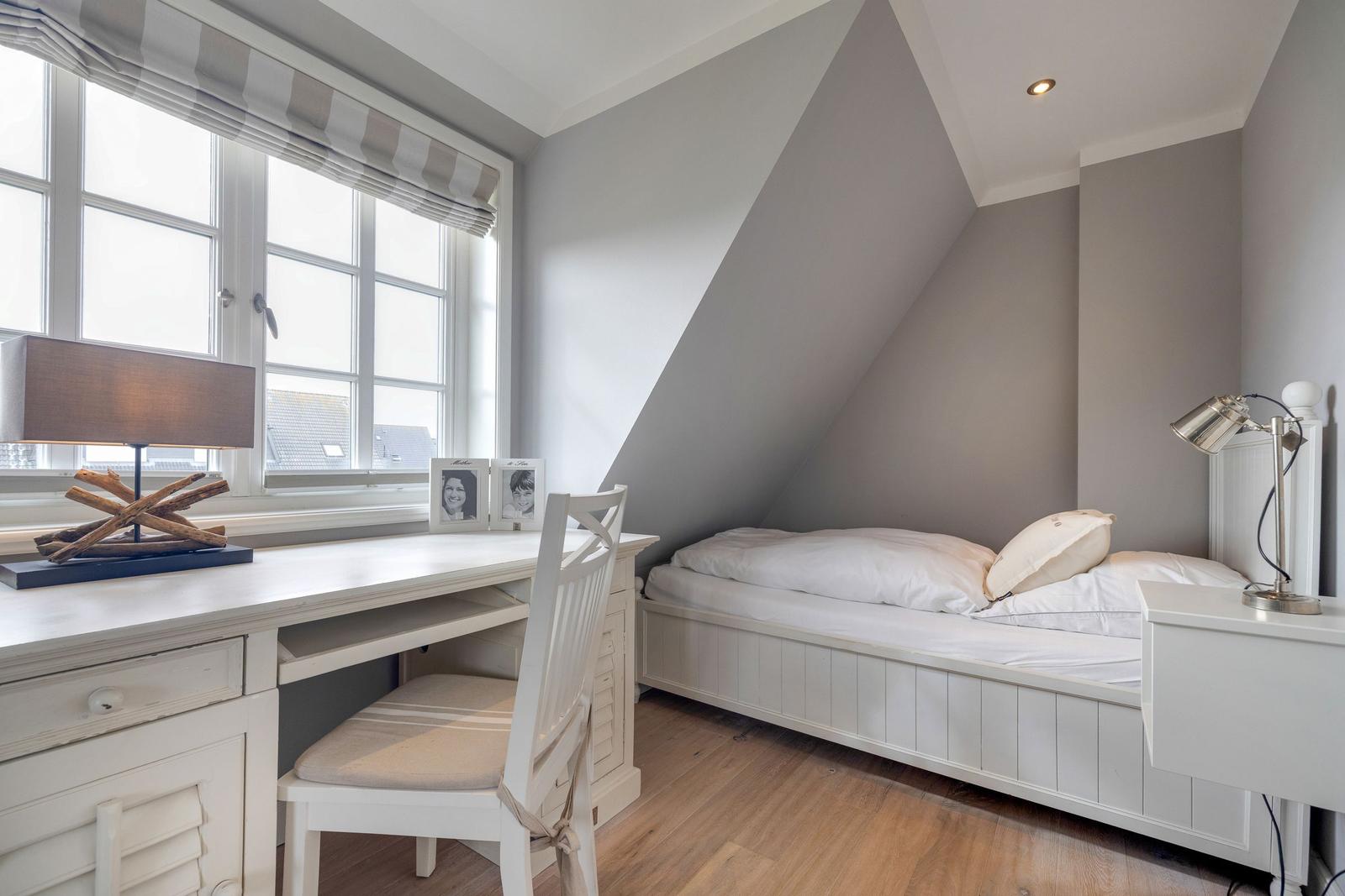 Schlafzimmer mit Dachschräge, Schreibtisch und Bett
