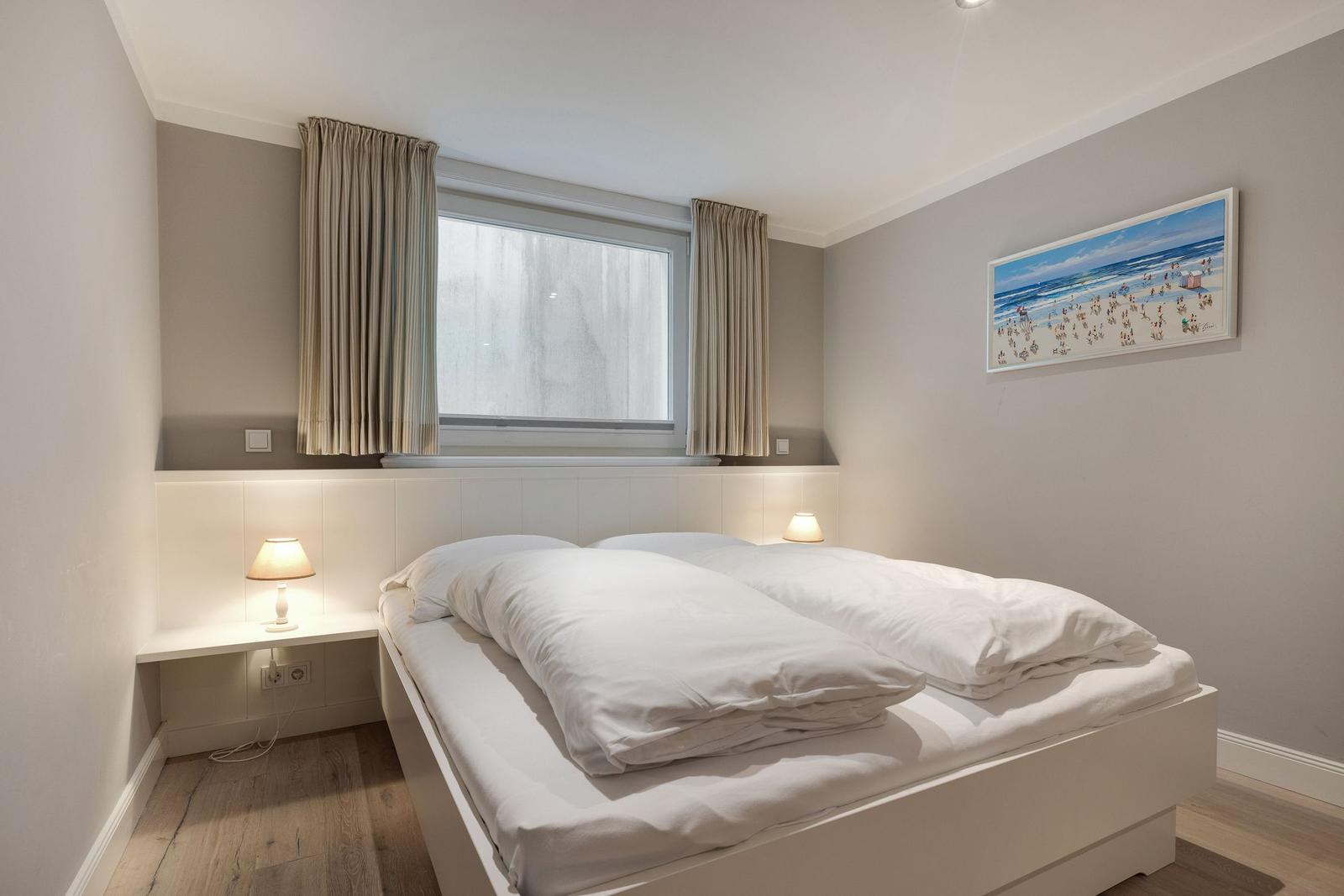 Schlafzimmer mit Doppelbett, Fenster und Wandbild.