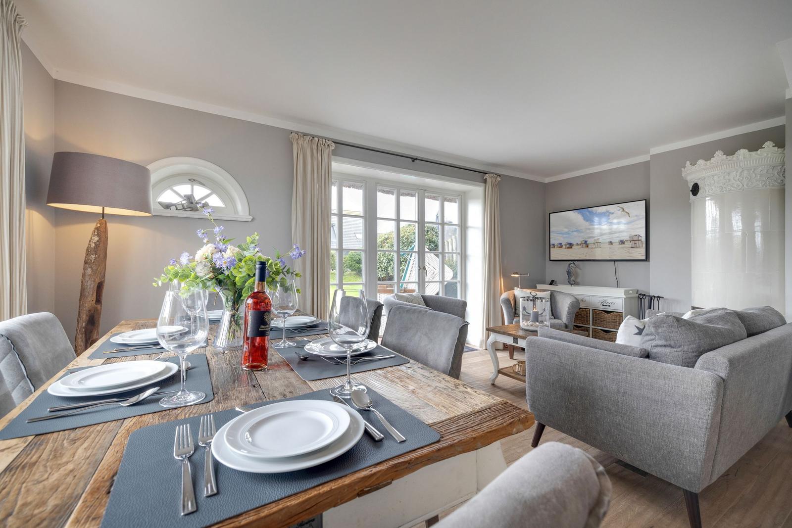 Esszimmer mit rustikalem Tisch und grauen Stühlen. Wohnbereich mit Sofa und Fernseher.