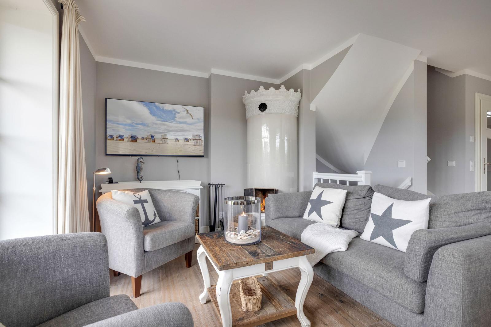 Wohnzimmer mit Sofa, Sessel, Kamin und Fernseher an der Wand.