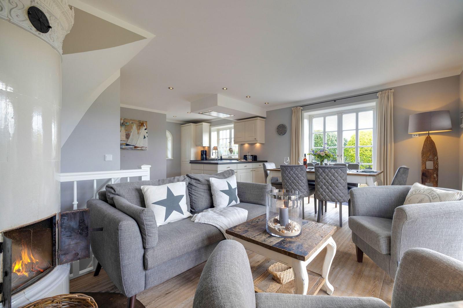 Wohn- und Essbereich mit Kamin, Sofa und Küchenbereich im Hintergrund.