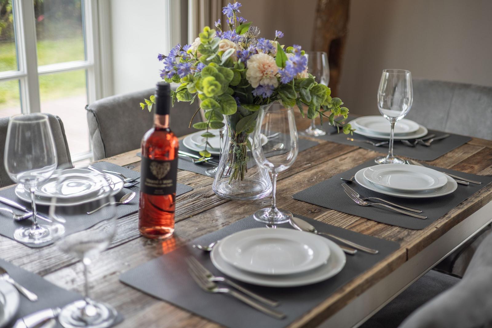 Esszimmertisch mit Platzierung, Blumenstrauß und Weinflasche.