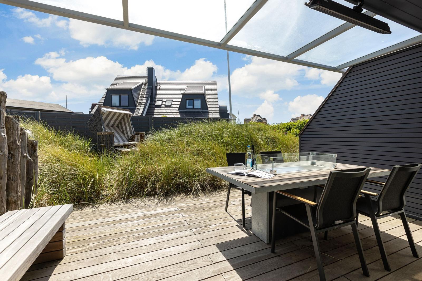 Terrace with table, chairs, and view of grass and house.