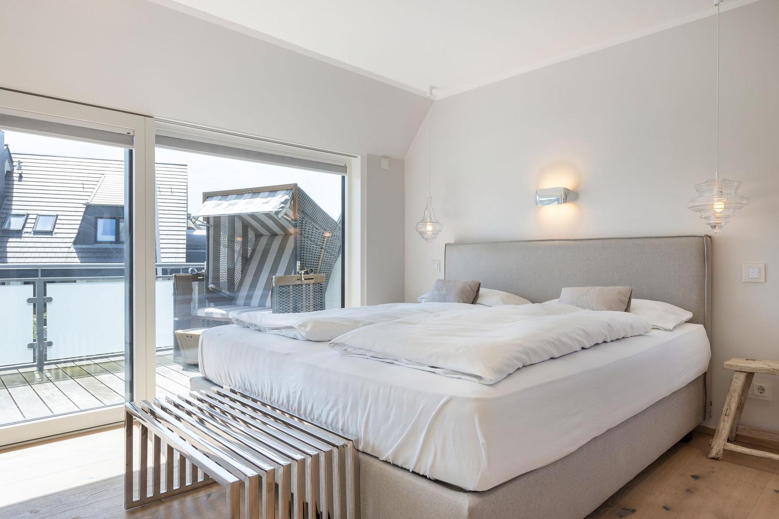 Bedroom with large bed and balcony view.