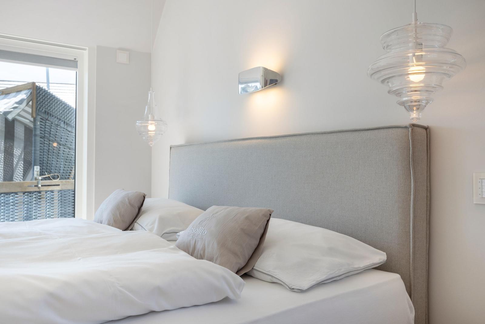 Bedroom with bed, headboard, and lamps on the wall