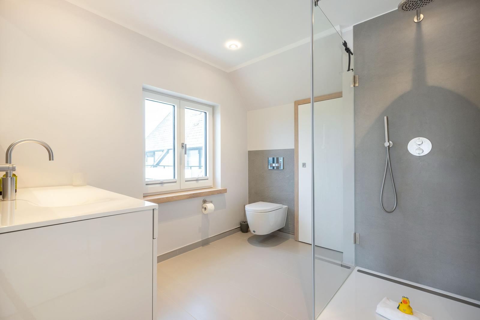 Bathroom with shower, sink, and toilet. Window with wooden windowsill.