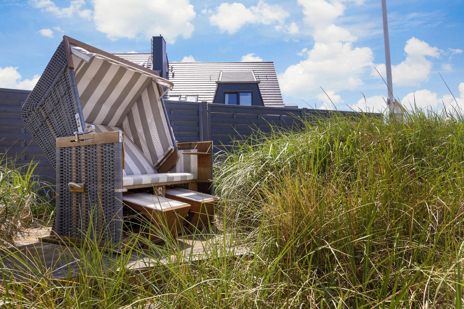 Beach chairs stand in grass in front of a house.