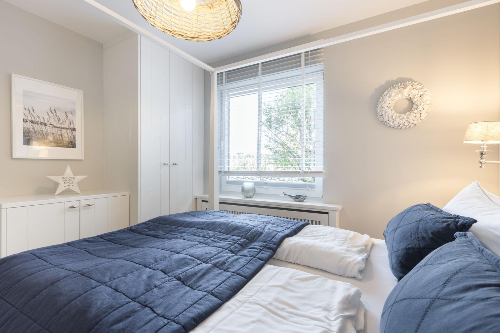 Bedroom with bed, window, and wardrobe.