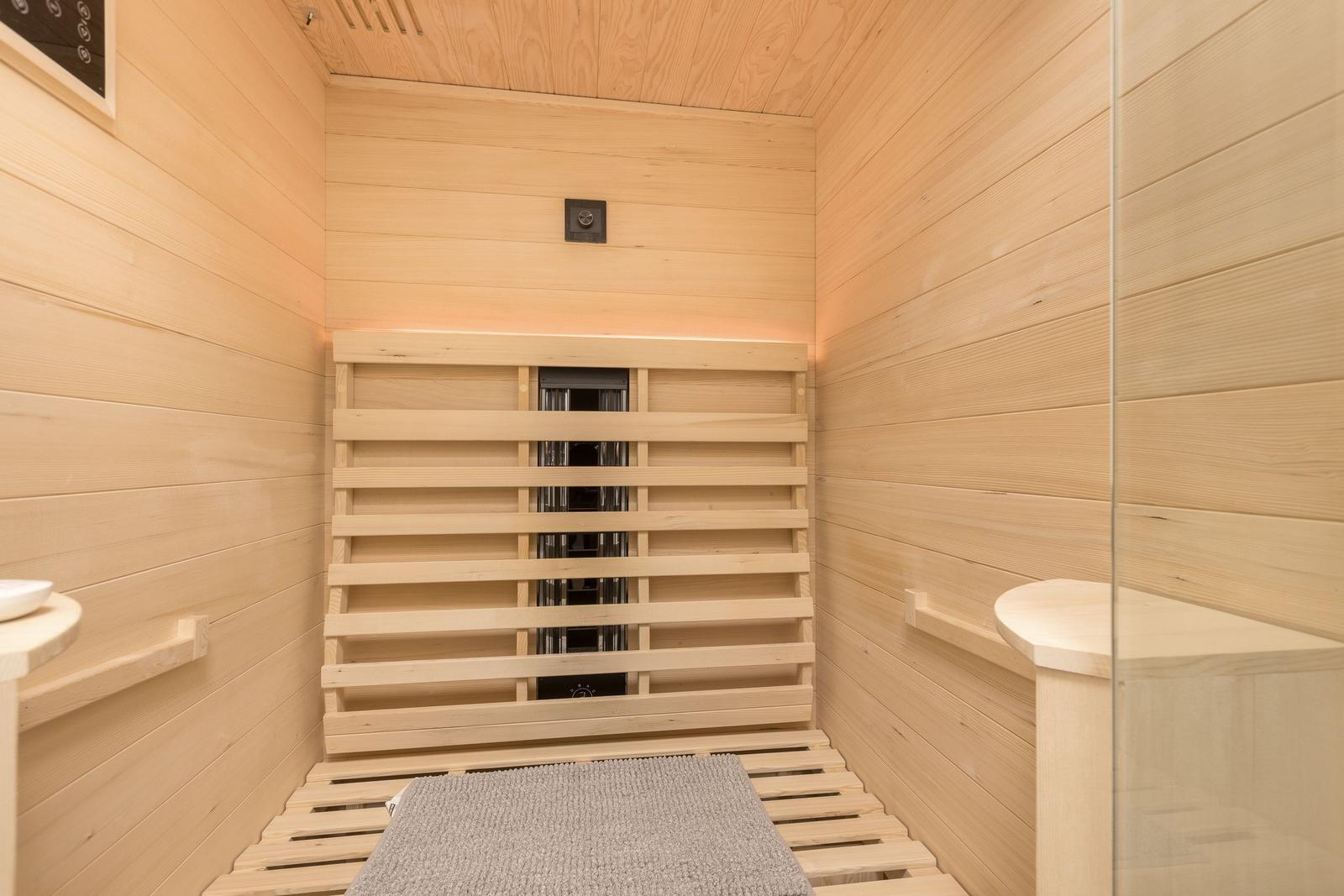 Sauna with wooden walls, benches, and floor mat.