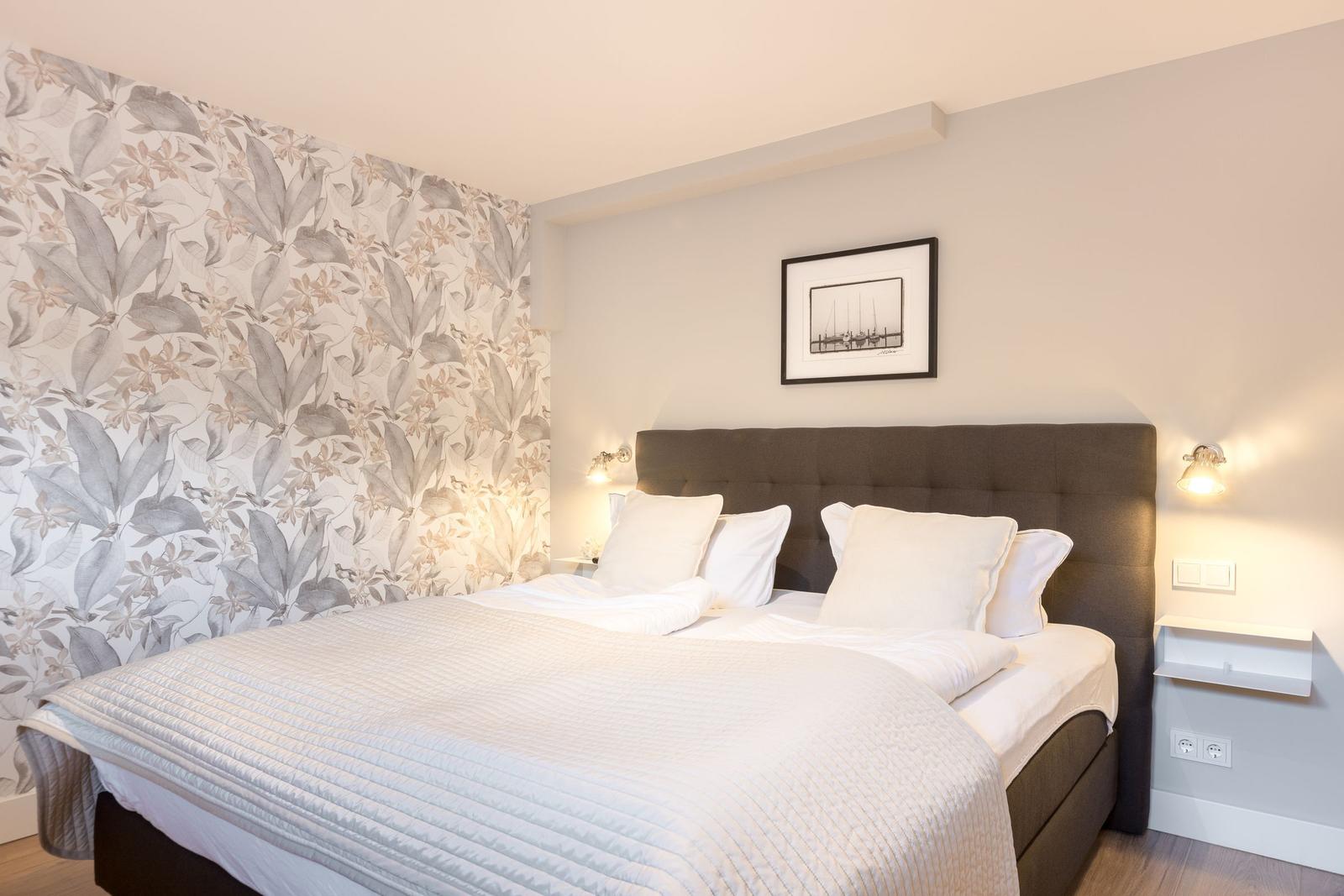 Bedroom with bed, headboard, and floral wallpaper.