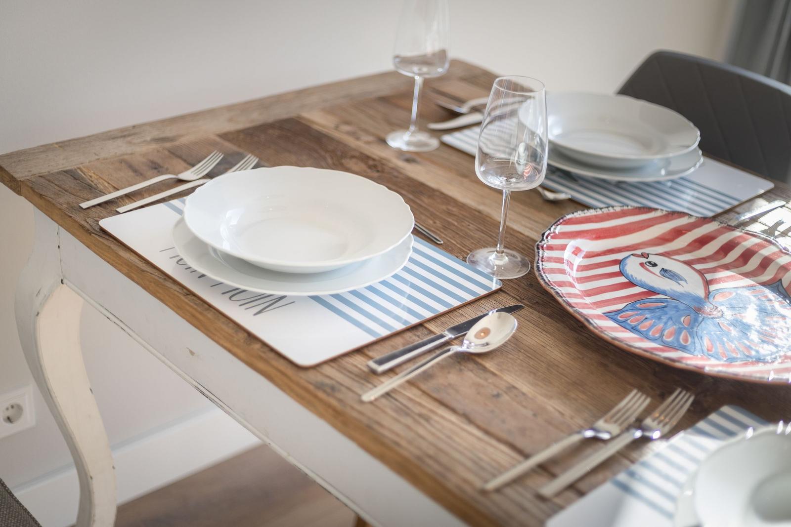 Wooden table set with dishes and place settings for guests