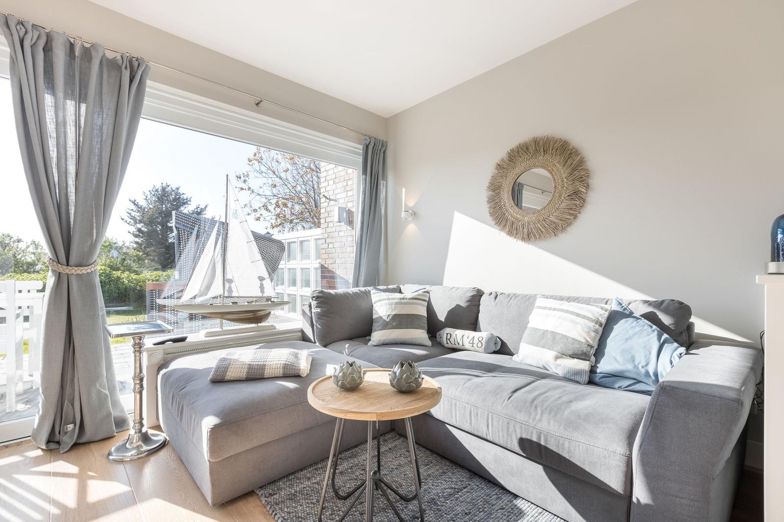 Gray sofa with cushions, round table, and mirror on the wall.
