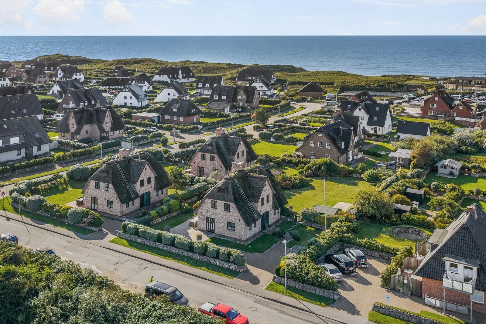 Dorf mit strohgedeckten Häusern und Blick auf das Meer