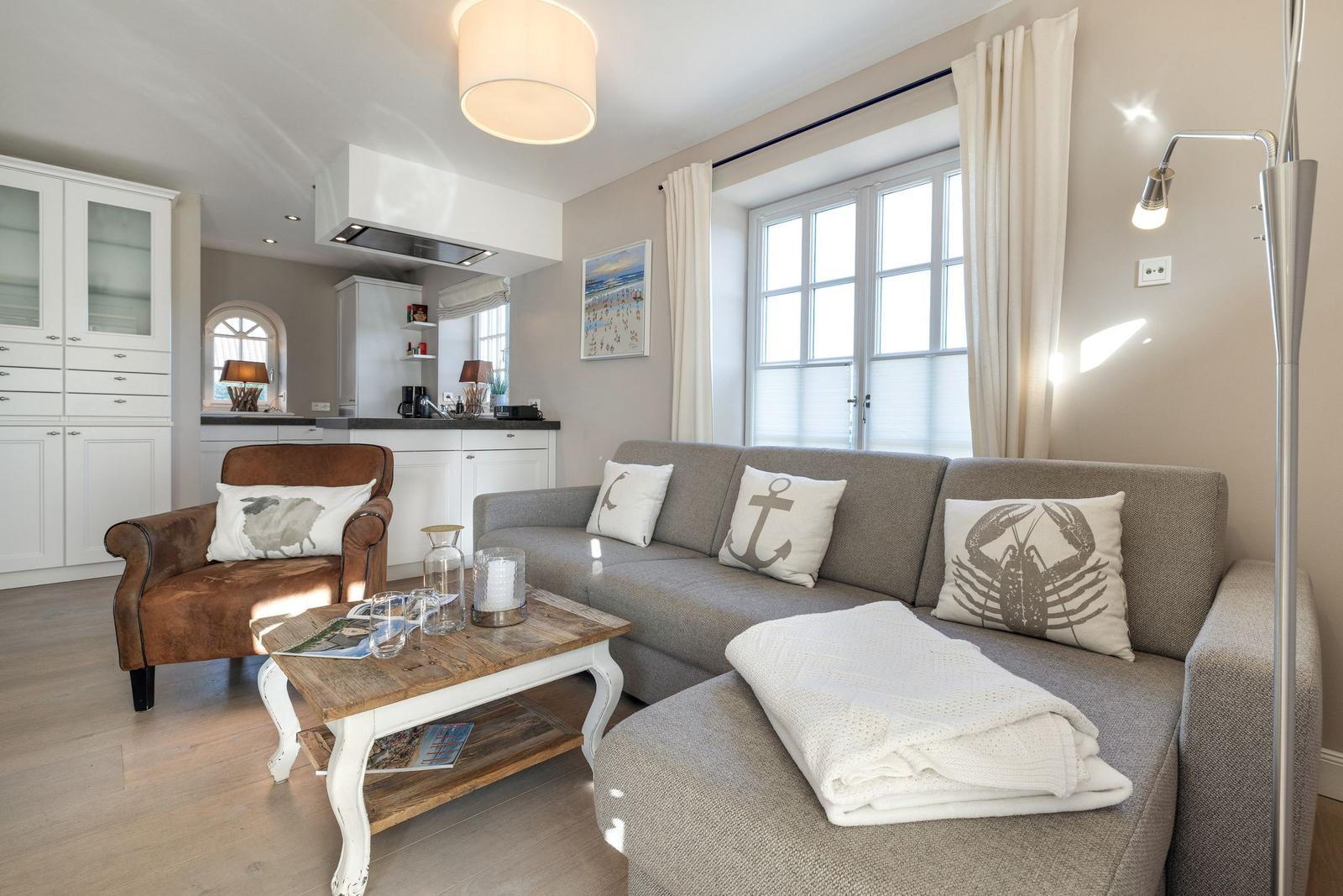 Wohnzimmer mit Sofa, Couchtisch und Küchenbereich im Hintergrund.
