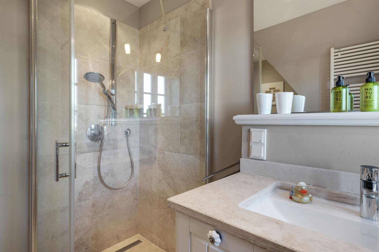 Dusche mit Glaswand und Waschbecken mit Spiegel