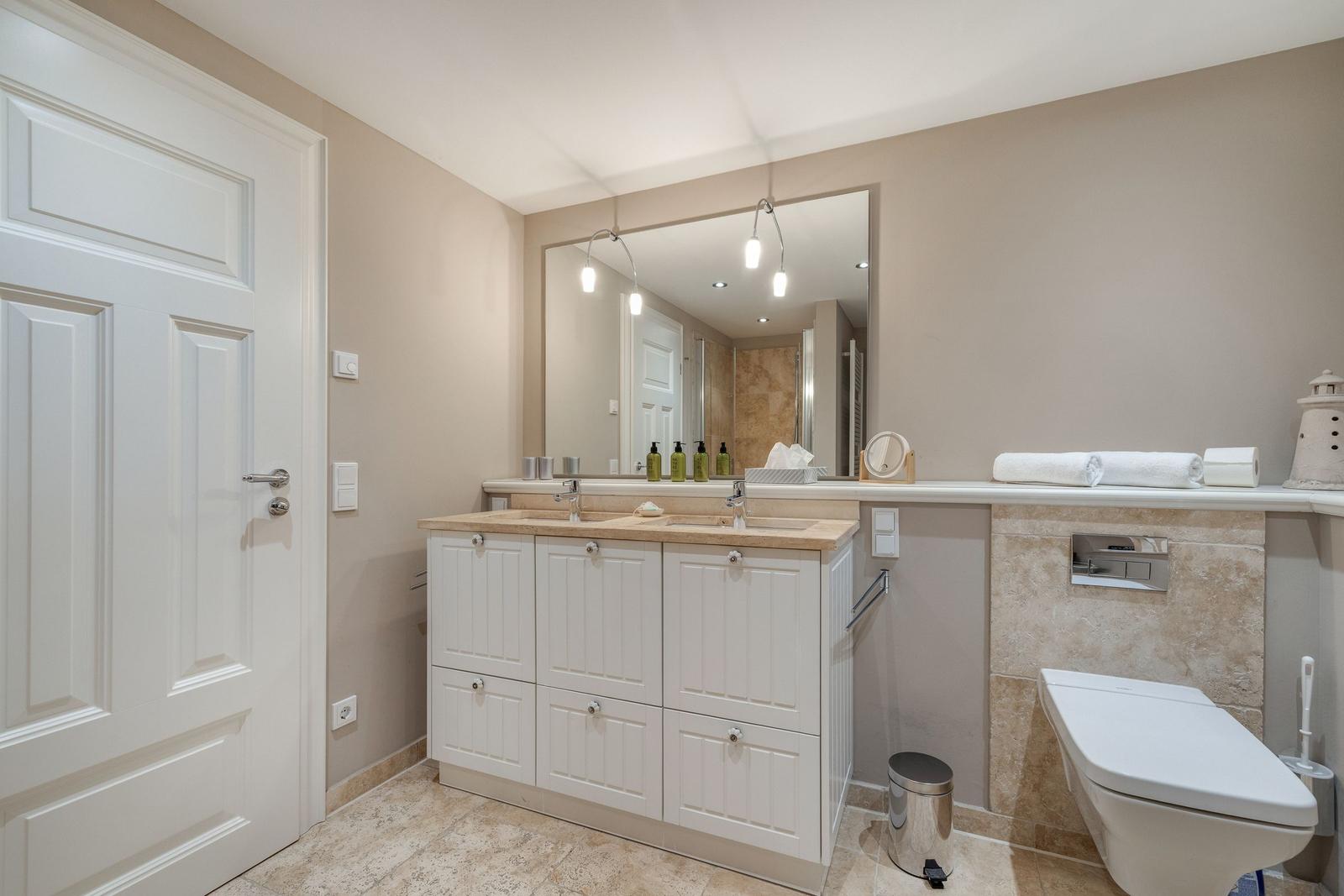 Badezimmer mit Waschbecken, Spiegel und Toilette