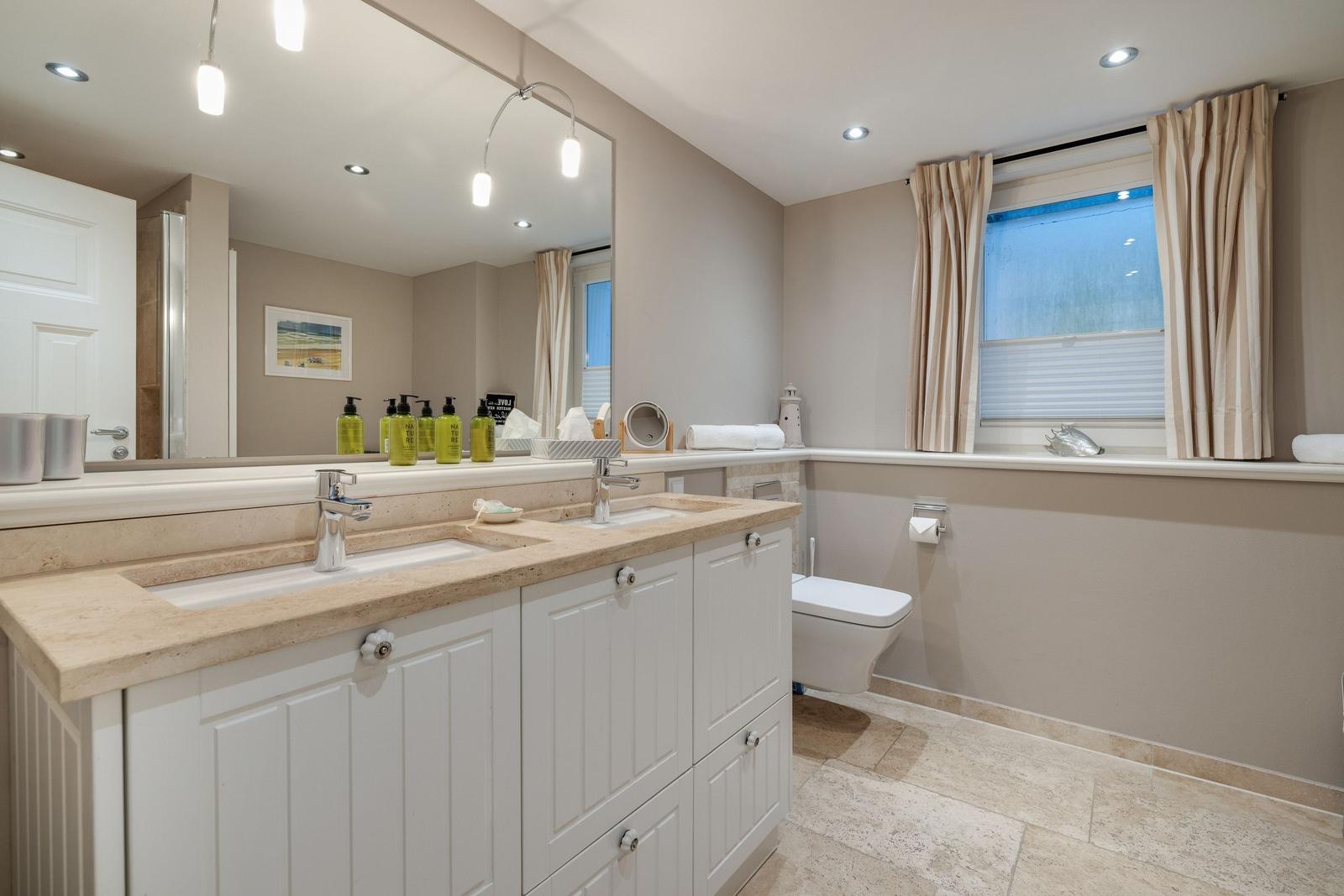 Badezimmer mit Waschbecken, Spiegel und Fenster