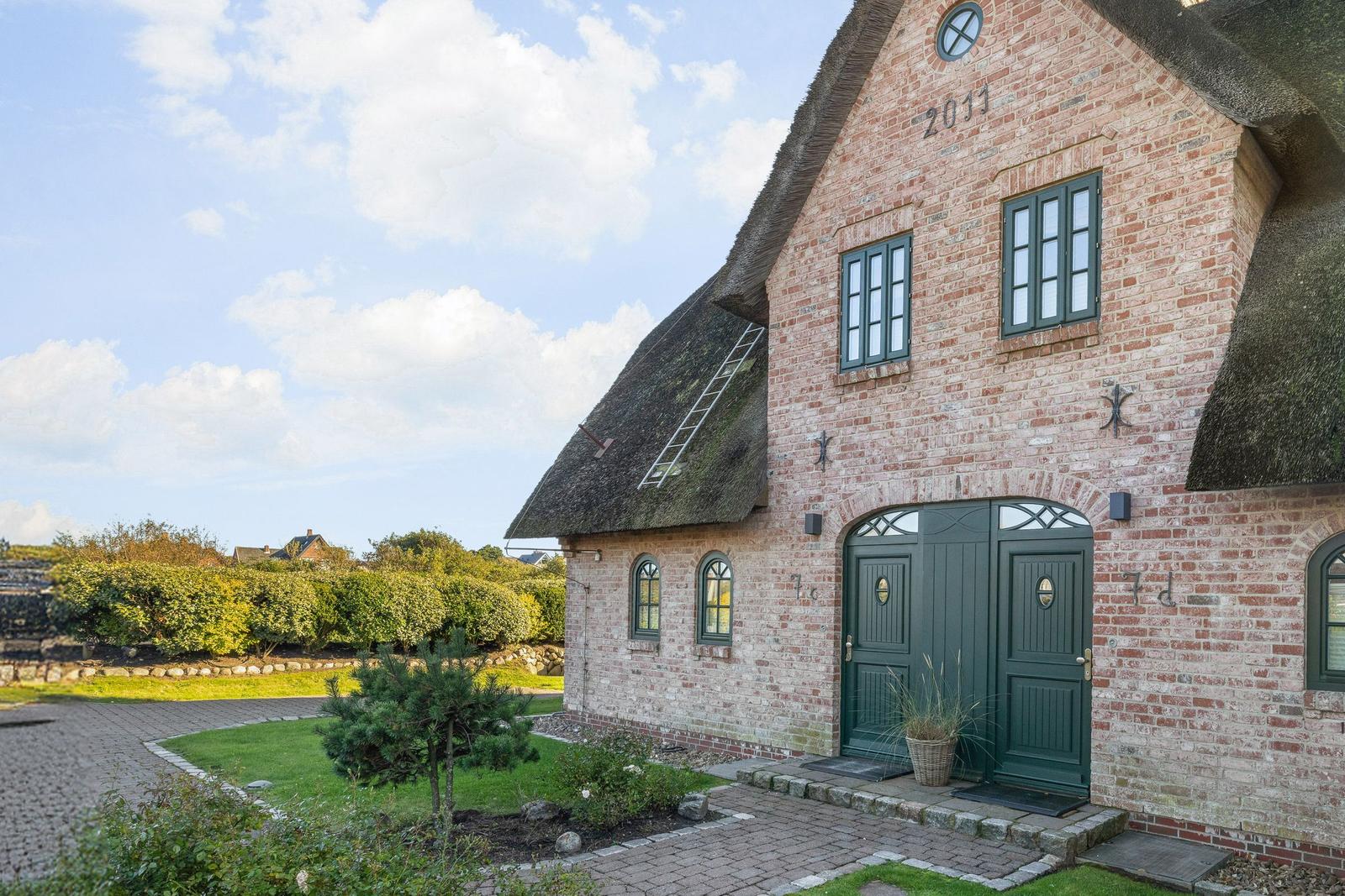 Haus mit strohgedecktem Dach und grünen Türen