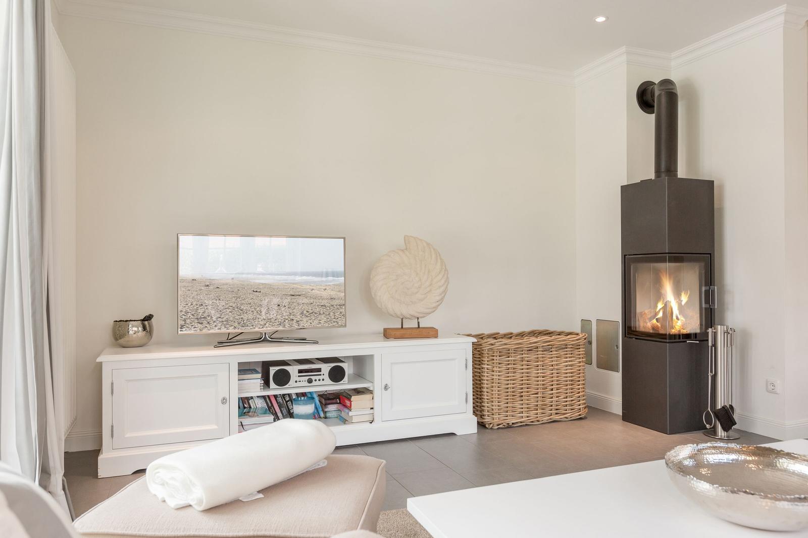 Wohnzimmer mit Fernseher, Kamin und Wickerkorb.