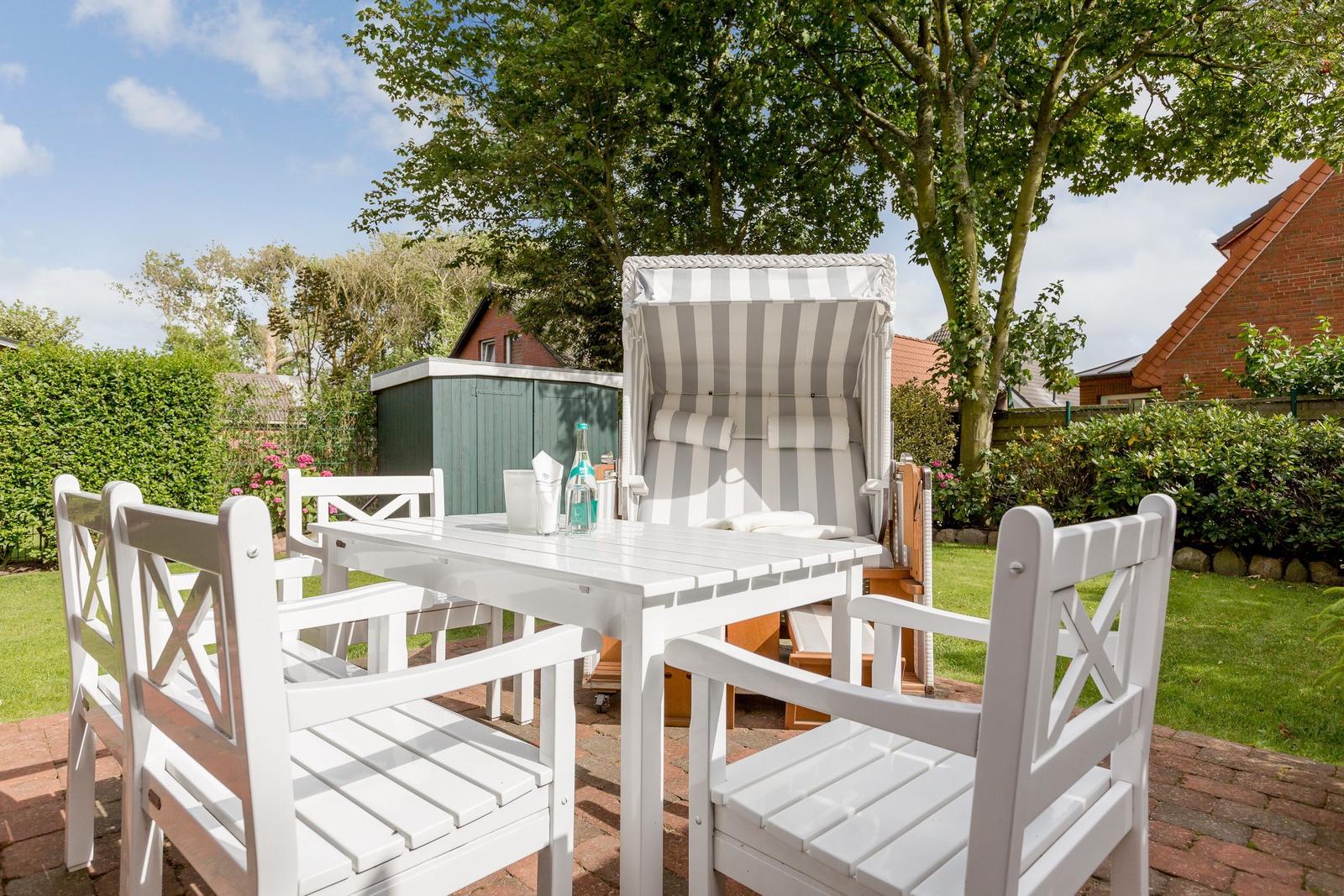 Weiße Terrassenmöbel mit Sonnenschutz und Tisch im Garten.