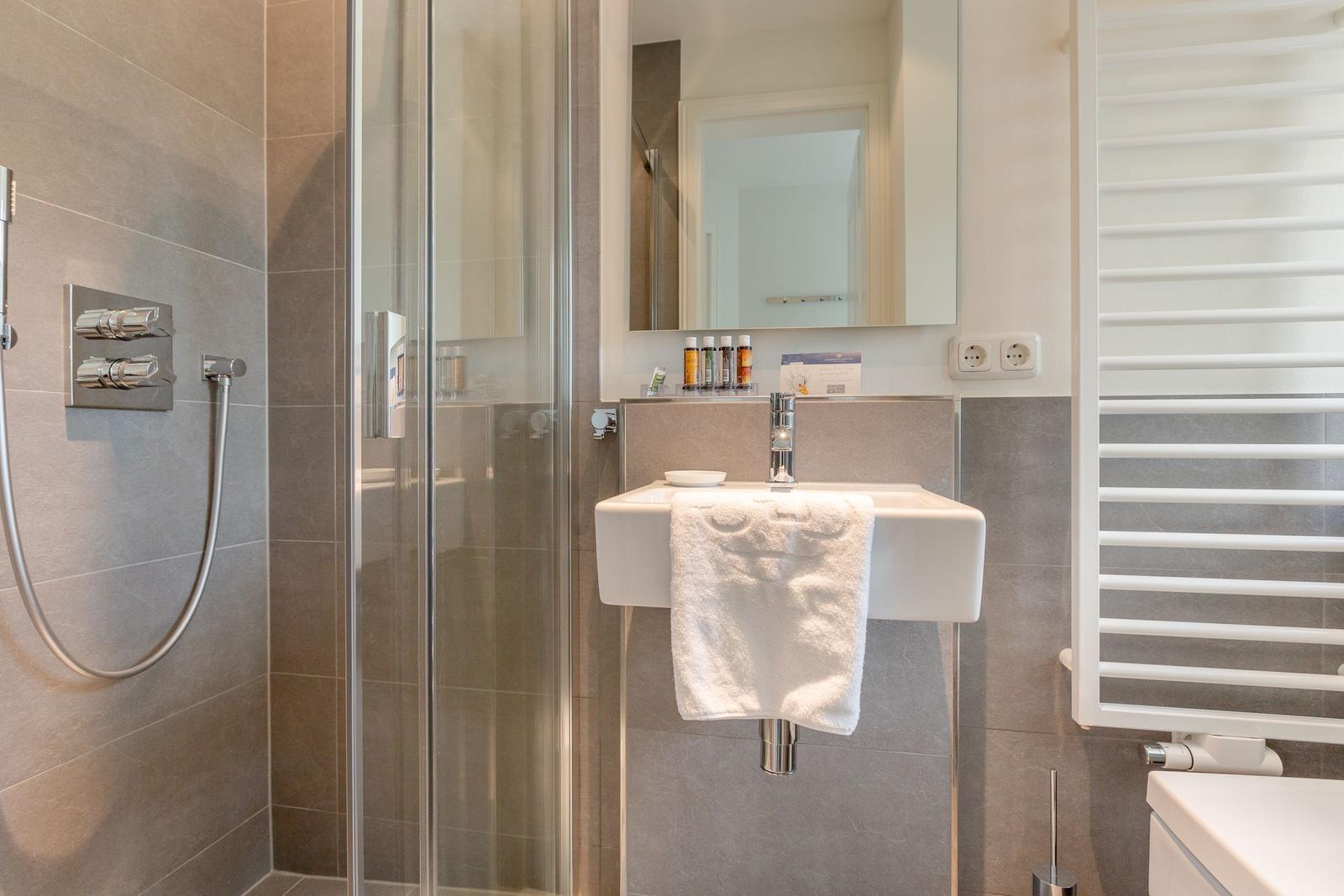 Dusche mit Duschbrause, Waschbecken und Heizkörper