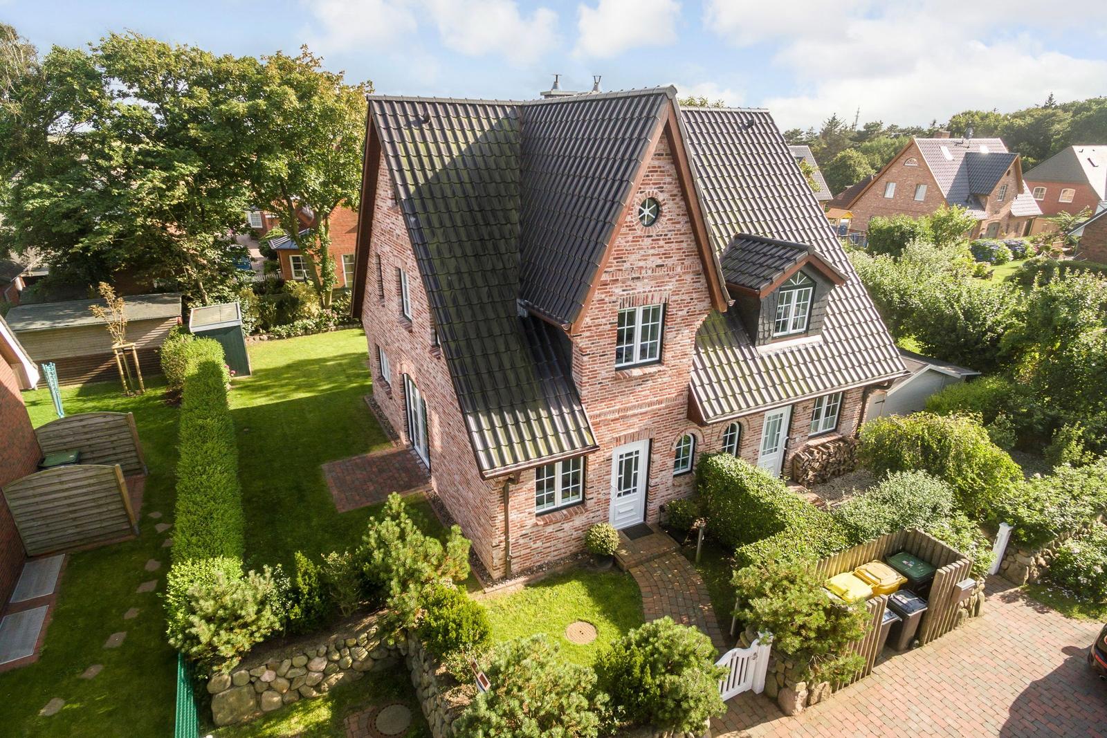 Zweistöckiges Backsteinhaus mit Dachgauben und gepflegtem Garten.