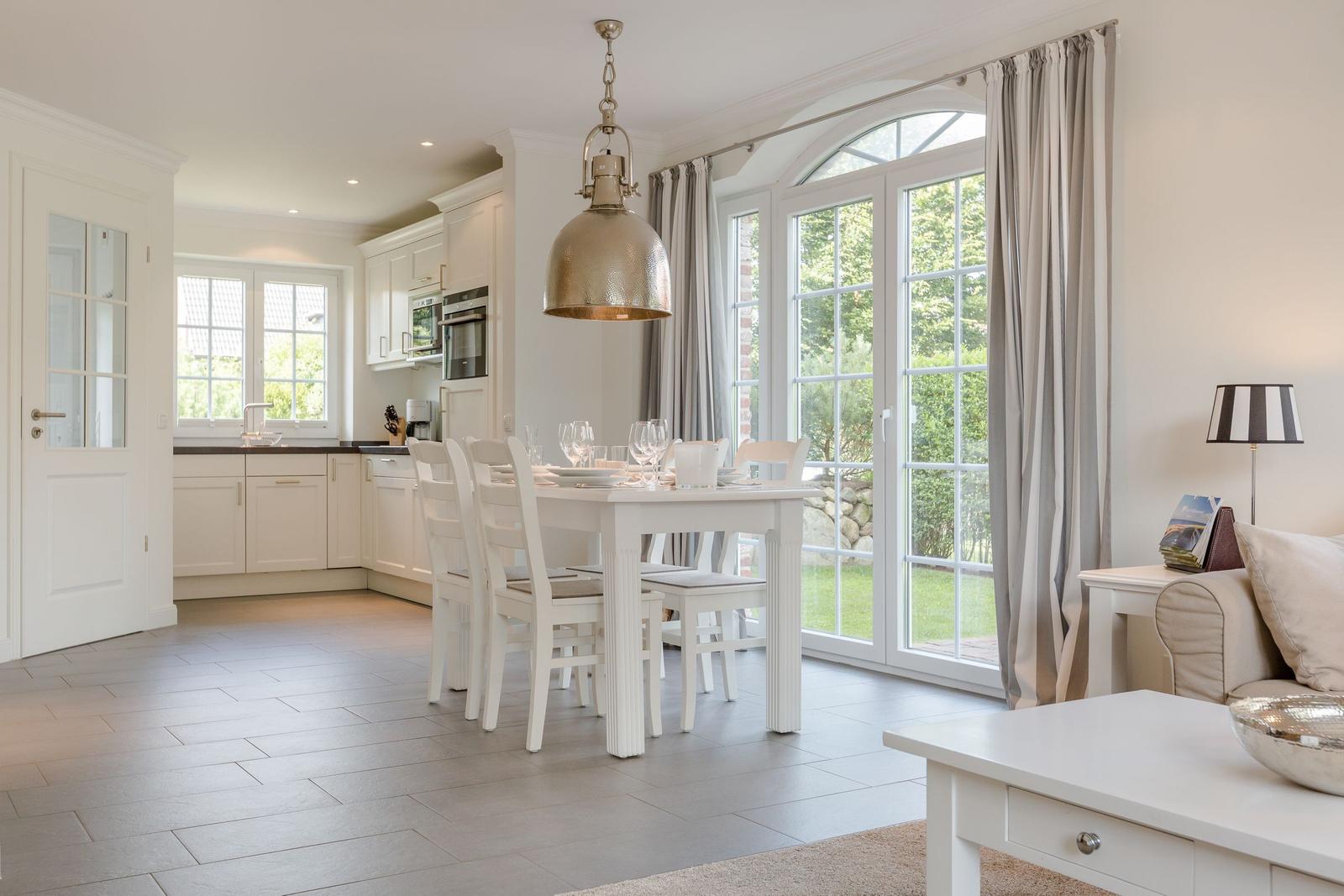 Essbereich mit Tisch und Stühlen vor großem Fenster mit Blick auf Garten.