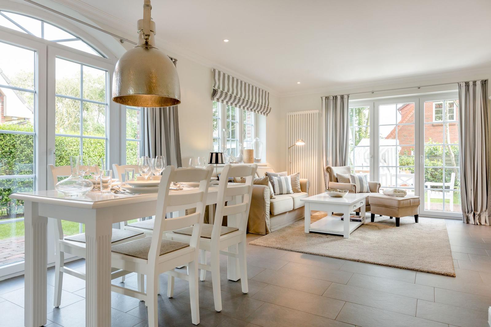 Esszimmer und Wohnbereich mit Tisch, Stühlen, Sofa und Glasfronten.