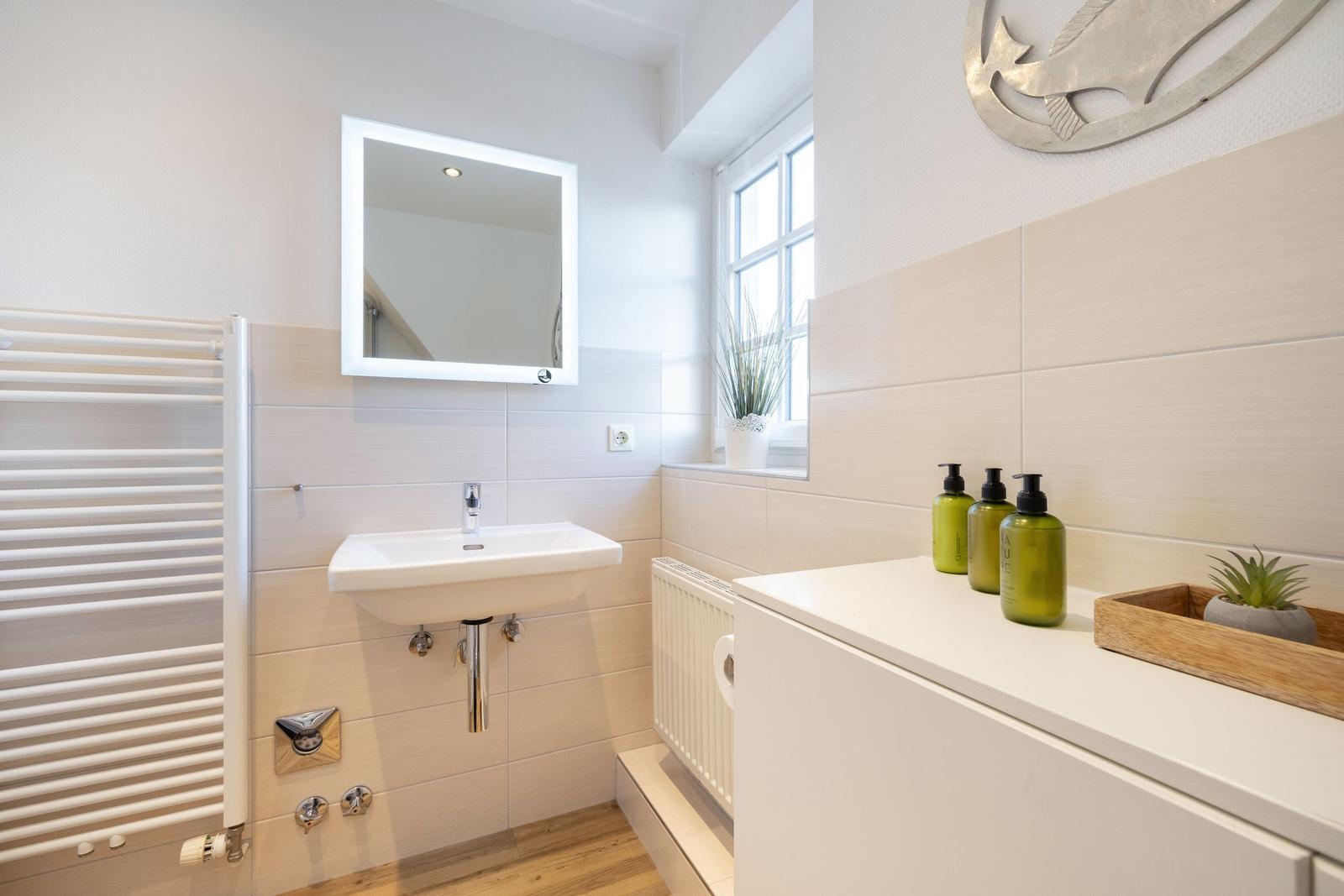 Bathroom with sink, mirror, window, and towels.