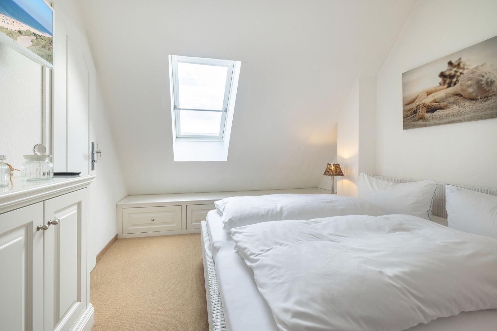 Bedroom with skylight, bed, and cabinet. Wall art with seashells.