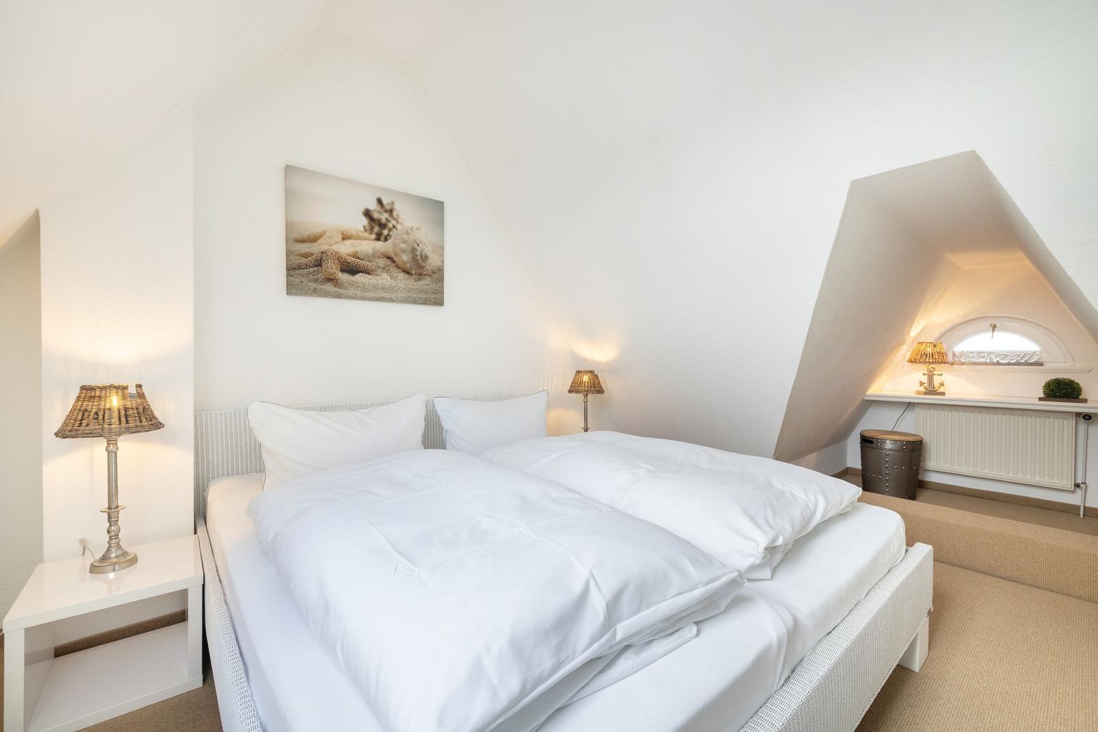 Bedroom with double bed, two nightstands, and wall art with shells.