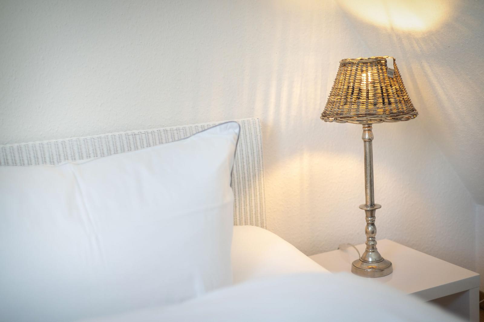 Bed headboard with pillow and nightstand with lamp.