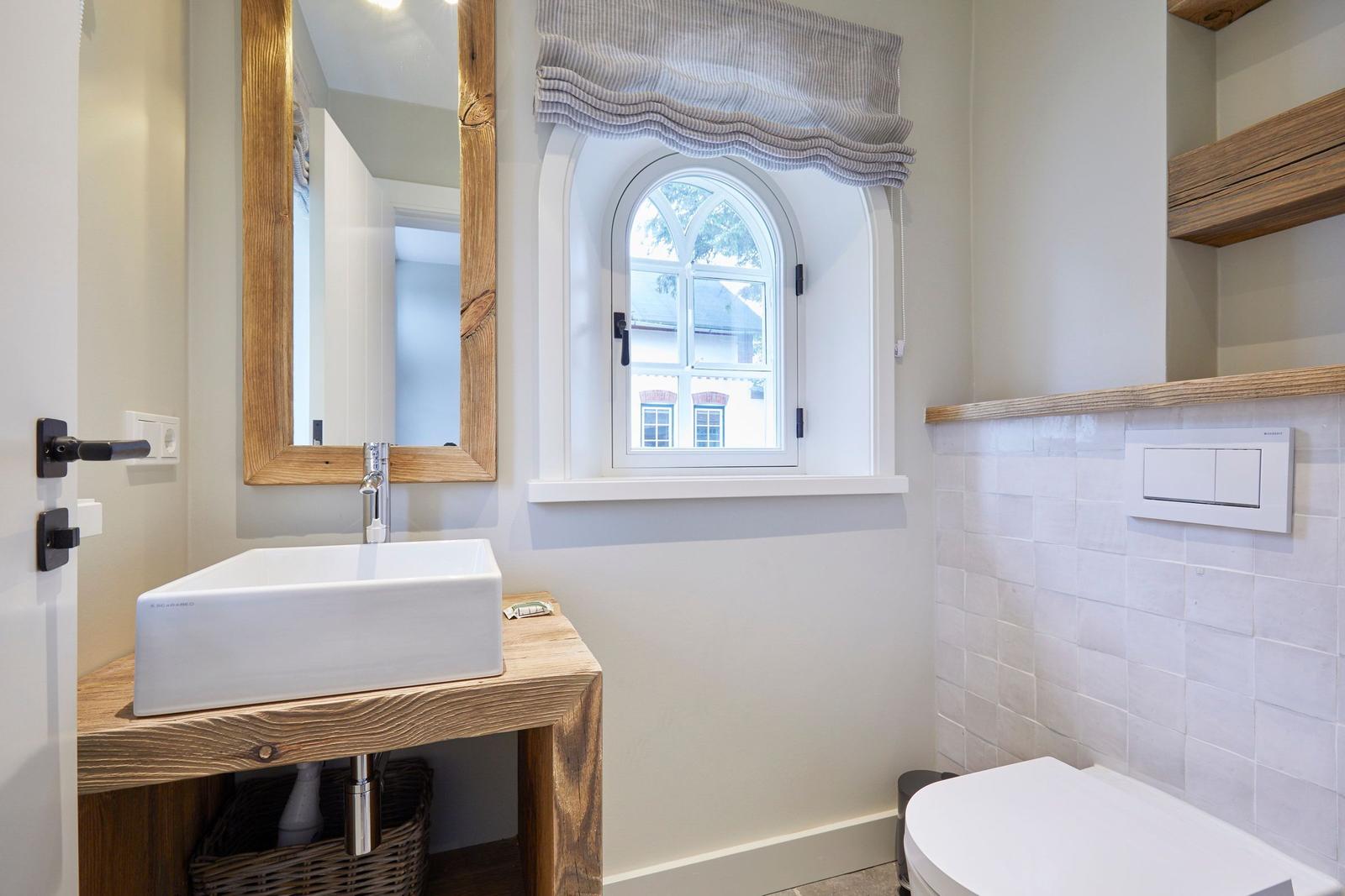 Badezimmer mit Waschtisch, Spiegel und Fenster