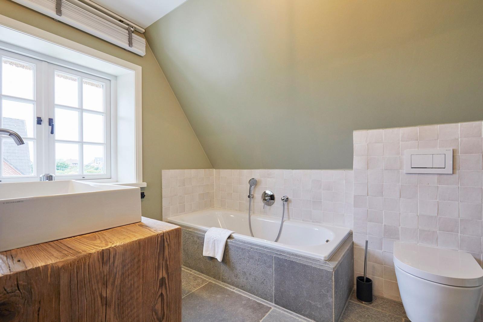 Badezimmer mit Badewanne, Fenster und Toilette.