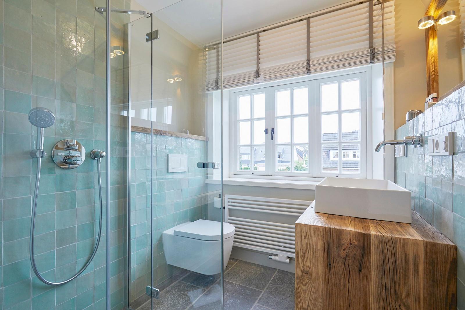 Badezimmer mit Dusche, Toilette und Waschtisch aus Holz.